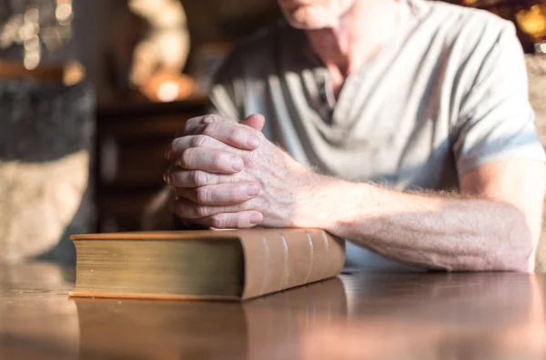 Homme priant les mains sur une Bible — Photo