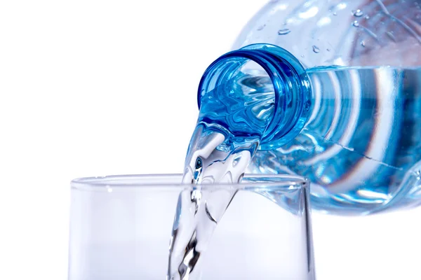 Agua vertida de una botella de plástico en un vaso —  Fotos de Stock