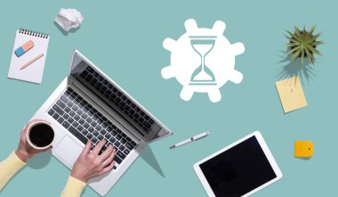 Zaman yönetimi kavramının sembolü olan dizüstü bilgisayar kullanan ellerin üst görünümü