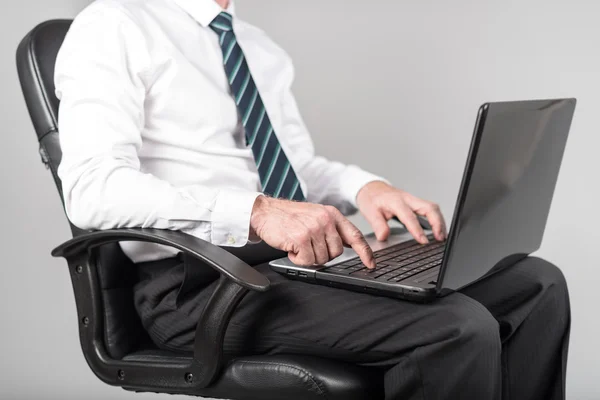 Empresario sentado y escribiendo en su portátil — Foto de Stock