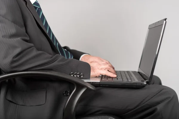 Empresario sentado y escribiendo en su portátil — Foto de Stock