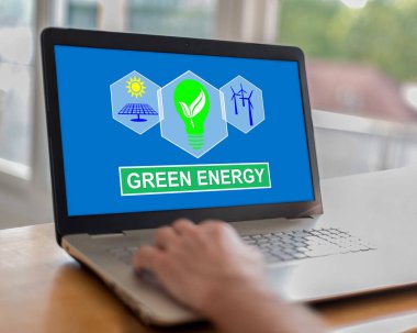 Ekranda yeşil enerji konsepti olan bir dizüstü bilgisayar kullanan adam