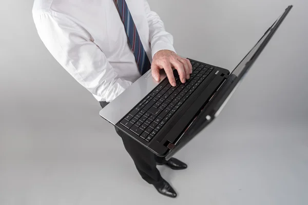 Empresario de pie, escribiendo en el ordenador portátil — Foto de Stock