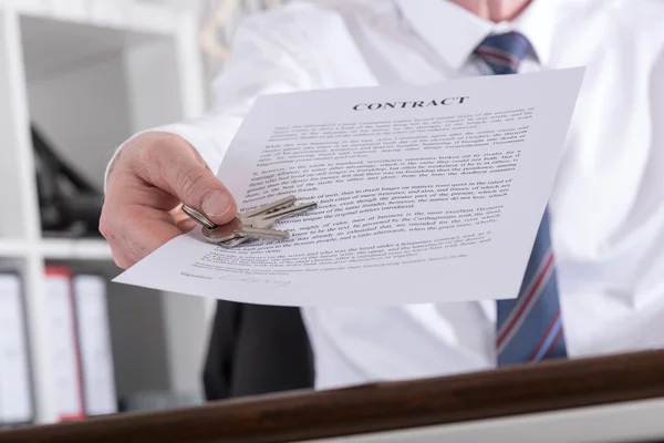 Onroerende goederenagent geven sleutels met contract — Stockfoto