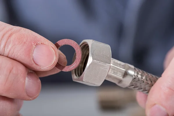 Loodgieter zet een pakking op een sanitair fitting — Stockfoto