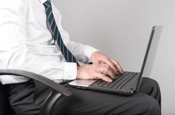 Geschäftsmann sitzt und tippt auf seinem Laptop — Stockfoto