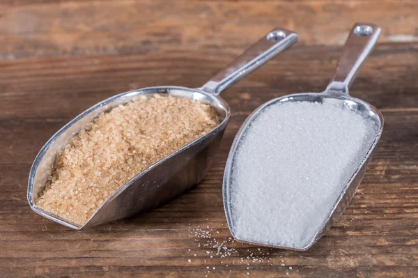 Белый и коричневый сахар в металлических лопатах — стоковое фото