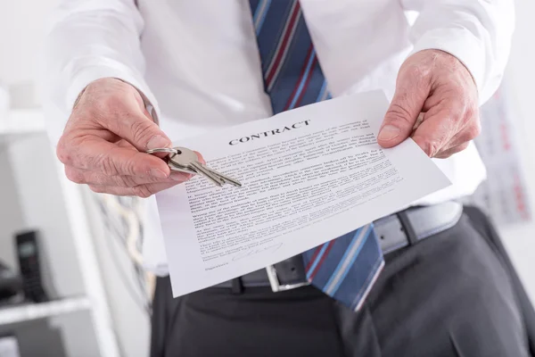 Onroerende goederenagent geven sleutels met contract — Stockfoto