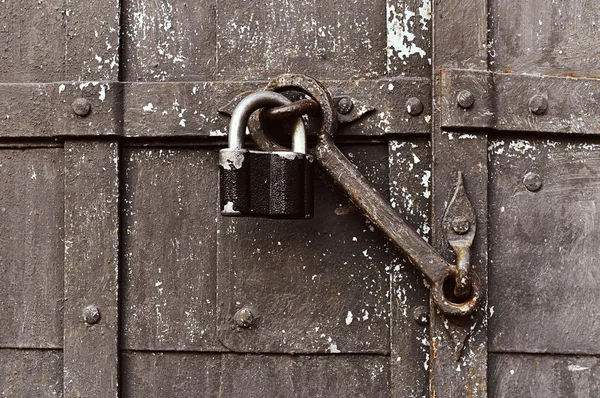 Steel padlock keeping the old door heck at the iron forged old door.