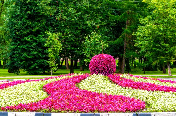 Street landscaping - picturesque flowerbed with landscaping feature in form of big apple covered with pink begonia flowers.