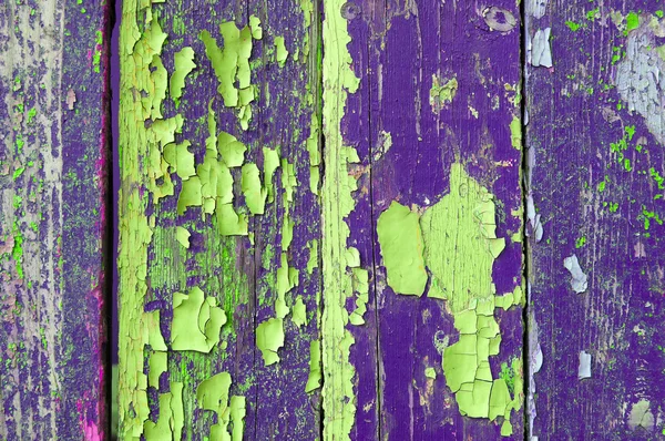Peeling bright violet and lemon yellow paint on old weathered wood - textured background