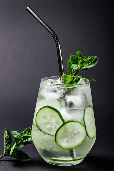 cucumber and mint lemonade in a glass on black table background with metal tube