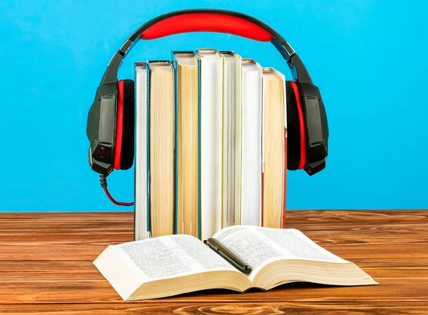 Concept for audio books, stack of books and headphones on a blue background.
