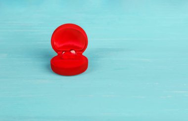 Kırmızı kadifeden yapılmış bir hediye kutusu ve mavi bir kalbi var. Sevgililer Günü. Boşluğu kopyala.