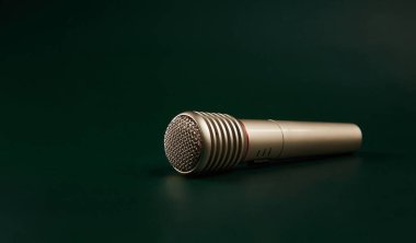 Koyu yeşil arka planda mikrofon yakın plan..