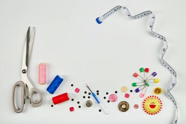 Mavi bir masaya aksesuar dikiyorum. Dikiş iplikleri, iğneler, iğneler, düğmeler, makas, dikiş santimetresi ve kesicinin mezurası. Boşluğu kopyala.