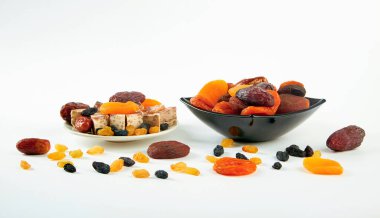 Beyaz arka planda bir tabakta kurutulmuş meyve karışımı.