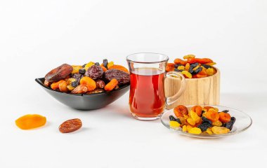 Bir fincan çay ve beyaz arka planda bir tabakta kurutulmuş meyve karışımı..
