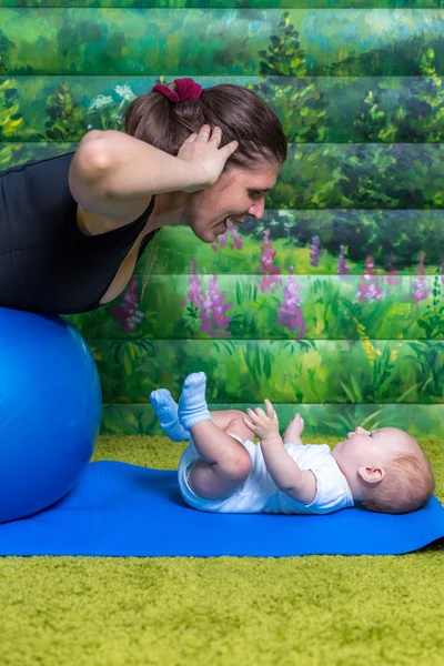 Anne ile bebek jimnastiği yapıyor