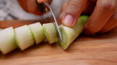 Japon Uzun Soğanı, Japon Scallion 'u ya da tahta kesme tahtasındaki Yeşil Soğan' ı kesmek için mutfak bıçağı kullanan bir kadın. Kadın mutfakta yemek hazırlıyor. Yemek pişirme konsepti.