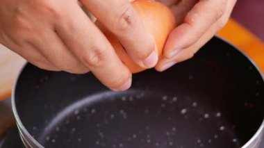 Sıcak tavada kızartılmış yumurta yakın plan. Kadın eli kırılır tavuk yumurtası mutfak tavasına düşer. Besleyici Kahvaltı Konsepti.