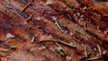 Tuz taneleri ve otlarla bezenmiş ızgara bir tabakta sulu et kızartması. Sağlıklı gıda konsepti.