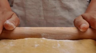 Un içindeki kadın eller hamuru ahşap bir masanın üzerinde yuvarlar hamuru pizza ya da çörek yapmak için hazırlar. Yemek pişirme süreci.