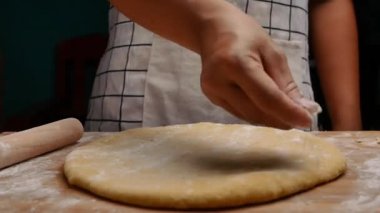 Un içindeki kadın eller hamuru ahşap bir masanın üzerinde yuvarlar hamuru pizza ya da çörek yapmak için hazırlar. Yemek pişirme süreci.