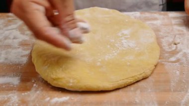Un içindeki kadın eller hamuru ahşap bir masanın üzerinde yuvarlar hamuru pizza ya da çörek yapmak için hazırlar. Yemek pişirme süreci.