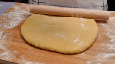 Un içindeki kadın eller hamuru ahşap bir masanın üzerinde yuvarlar hamuru pizza ya da çörek yapmak için hazırlar. Yemek pişirme süreci.