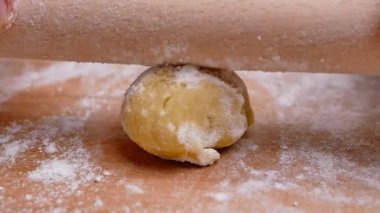 Un içindeki kadın eller hamuru ahşap bir masanın üzerinde yuvarlar hamuru pizza ya da çörek yapmak için hazırlar. Yemek pişirme süreci.