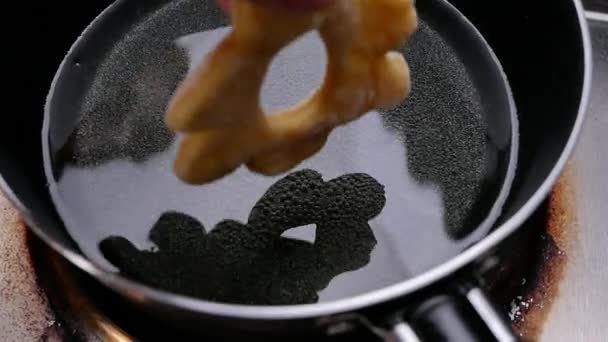 キッチンストーブの上の鍋に熱い油でおいしいと自家製のドーナツを飛んでいます 調理プロセス — ストック動画
