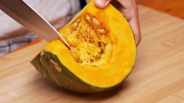 Balkabağını pişirmek için hazırlayan kadın ellerini kapat, kesme tahtasındaki bıçakla tohumları ayır. Sağlıklı yemek hazırlama kavramı.