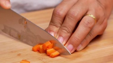 Kesme tahtasındaki bıçakla kadın ellerinin çiğ havuçları keserek sopa haline getirmesi..