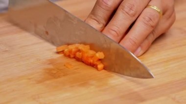 Kesme tahtasındaki bıçakla kadın ellerinin çiğ havuçları keserek sopa haline getirmesi..