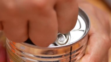 Eller konserve kutusunu açıyor, yakın plan. Konserve kutusunu çekme sekmesiyle açmayı gösteriyorum. Mutfakta bozulamaz gıda depolama ürünleri var..