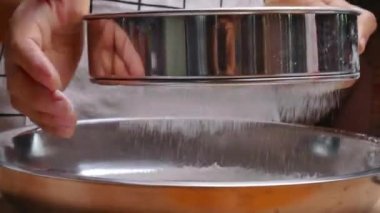 Lezzetli ev yapımı pizza hamuru yapmak için un filtresiyle paslanmaz çelik bir kabın içine süzen kadın elleri. Yemek pişirme süreci.