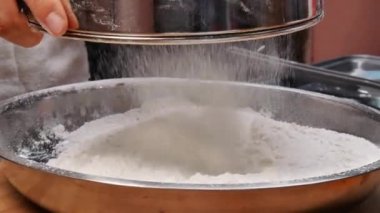 Lezzetli ev yapımı pizza hamuru yapmak için un filtresiyle paslanmaz çelik bir kabın içine süzen kadın elleri. Yemek pişirme süreci.