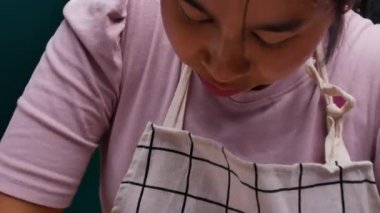 Önlüklü bir kadın paslanmaz bir kapta hamur yoğuruyor ve ev yapımı pizza yapmak için hamur hazırlıyor. Yemek pişirme süreci.