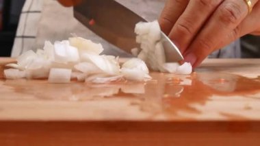Tahta kesme tahtasının üzerinde soğan doğrayan kadın elleri. Sağlıklı yemek hazırlama kavramı.