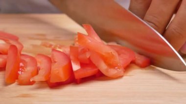 Tahta kesme tahtasında domates doğrayan kadın elleri. Sağlıklı yemek hazırlama kavramı.