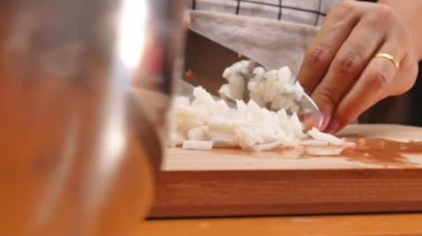 Tahta kesme tahtasının üzerinde soğan doğrayan kadın elleri. Sağlıklı yemek hazırlama kavramı.