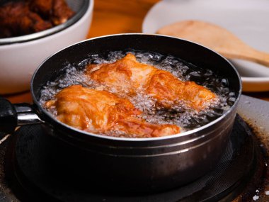 Mutfak ocağında tavuğu kızgın yağda kızartıyorum. Yemek pişirme konsepti.