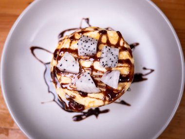 Üzerine ejderha meyvesi ve çikolata sosu dökülmüş lezzetli kreplerin kapağı. Kahvaltı için ev yapımı krep..