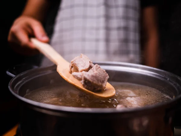 台所の電気ストーブの上の鍋に豚カルビで煮スープを攪拌女性の手 料理のコンセプト — ストック写真