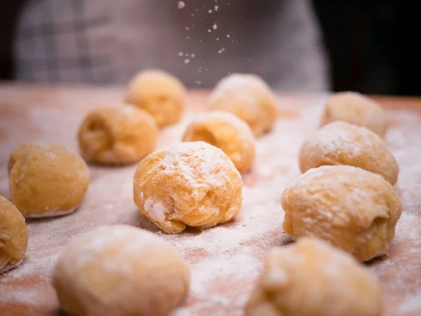 Bütün bir hamurdan bir parça hamur ve ahşap bir masada donut yapmak ve un serpiştirmek için toplar oluşturur. Yemek pişirme süreci.