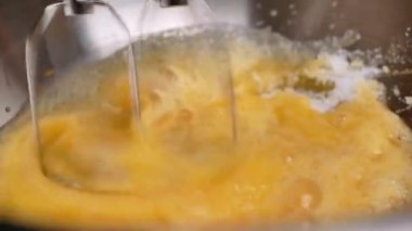 Kadın ellerinin paslanmaz çelik bir konteynırda elektrikli çırpıcı ile yumurtaları çırpmasını kapatın. Adım adım ev yapımı lezzetli çikolatalı kurabiyeler ya da çikolatalı kurabiyelerin tarifi.