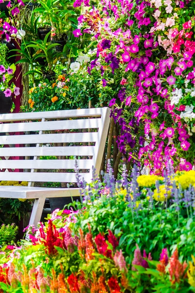 Biały drewno fotel w ogrodzie kwiaty. — Zdjęcie stockowe