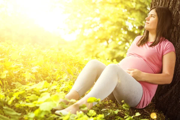 Femme enceinte assise sur l'herbe — Photo