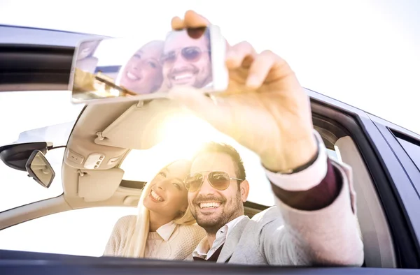 Pareja joven tomando una selfie en el coche — Foto de Stock